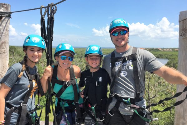 A family poses in the tree tops of a zip line adventure.
