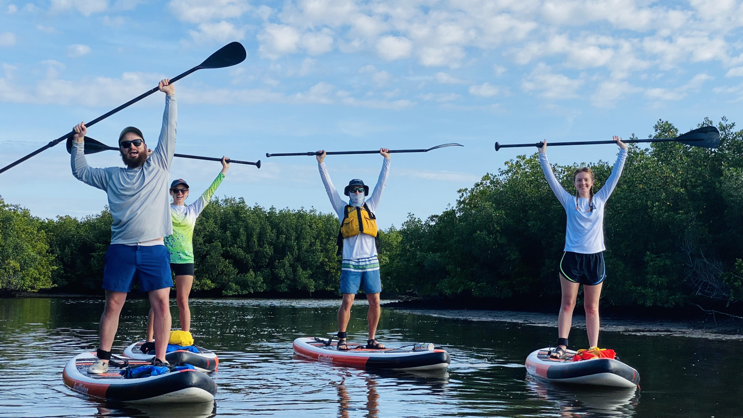 a group celebrates their first time stand up paddleboarding through mobbly bayou at empower adventures in tampa bay