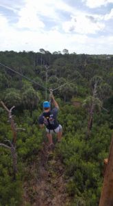 A man rides a Tampa Bay zip-line at Empower Adventures high in the trees near Mobbly Bayou Wilderness Preserve.