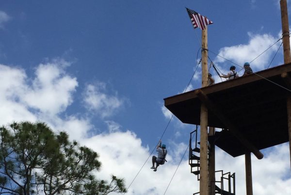 A man rides a zip line from a platform high in the trees at Empower Adventures.